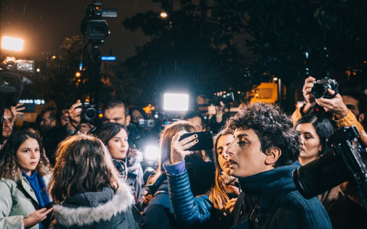 Multitud nocturna iluminada por cámaras y teléfonos